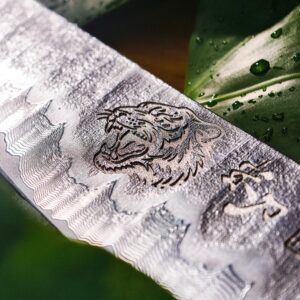 TIGRITUDE III blade close-up with a tiger head motif and flowing patterns near the cutting edge.