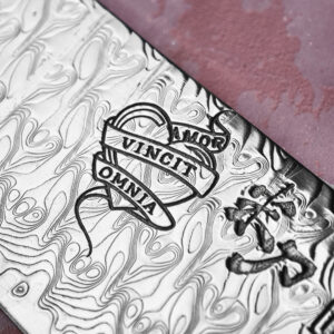AMOR II blade close-up showing a heart and banner reading 'Amor Vincit Omnia'.