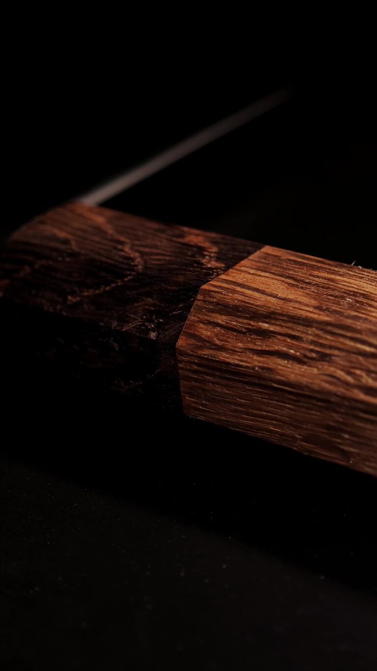 The oak handle of the RAW OAK THOR cleaver where it meets the blade, showing the grain.