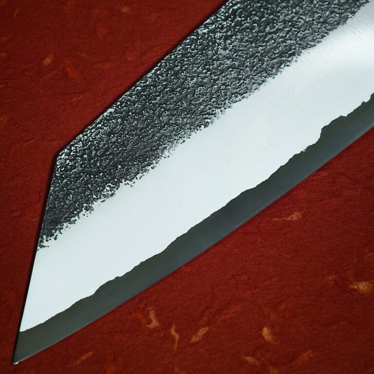 Blade tip: ash-dark area above, lighter steel toward the edge