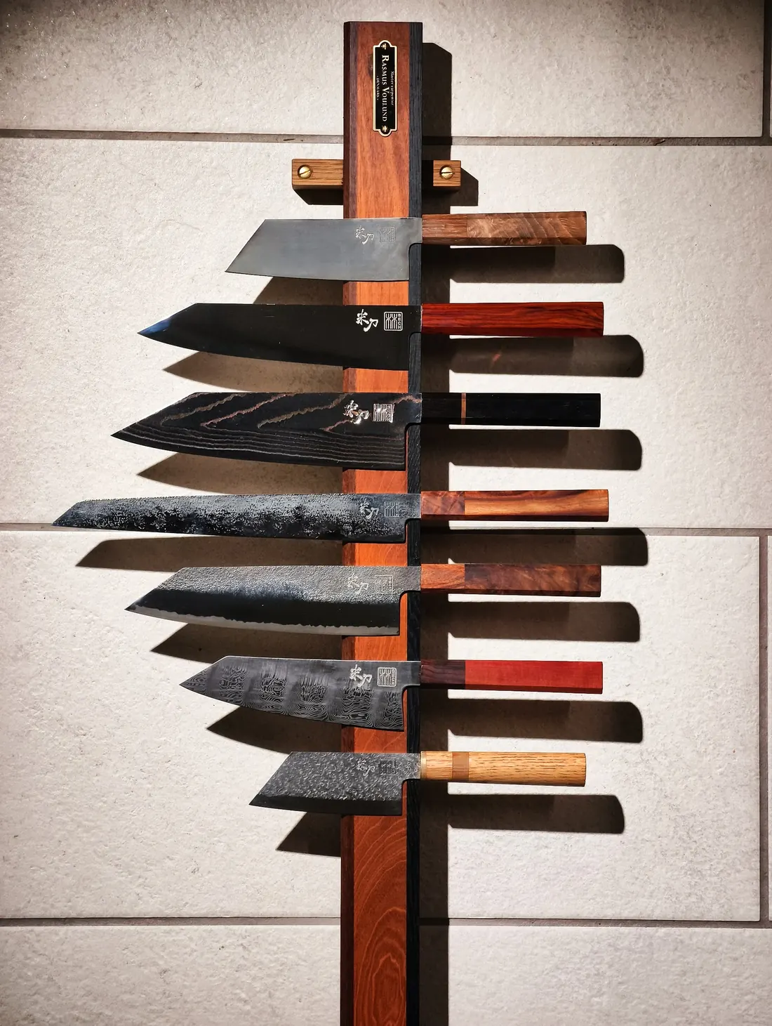 A row of custom knives with Damascus blades
