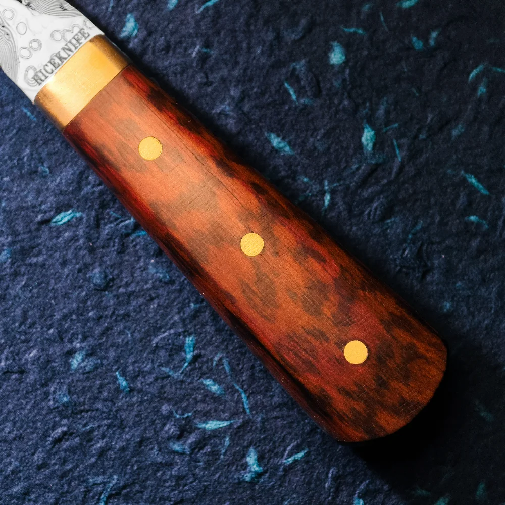 Snakewood handle close-up with darker speckles and three pins